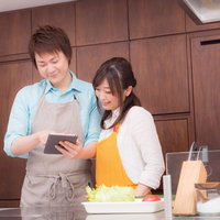 夕飯のレシピは何を作ろうかキッチンでタブレットを見る料理研究家の夫婦の写真