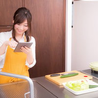 料理をはじめる前に、タブレットでレシピを確認する女性の写真