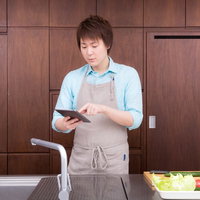 本日の献立をタブレットで確認する料理男子の写真
