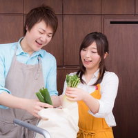 買い物袋から野菜を取り出して料理を始める男性と女性の写真