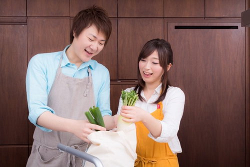 買い物袋から野菜を取り出して料理を始める男性と女性