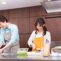 モダンキッチンで野菜を調理する若い夫婦の料理風景の写真