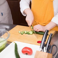 竹のまな板できゅうりを切る調理風景、野菜カットの写真