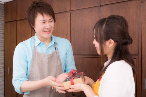 主人にバレンタインの手作りチョコレートケーキを渡す女性の笑顔