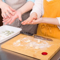 黄色いエプロン姿でニョッキを丸める女性の手作り料理の写真