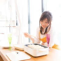 ホットプレートで餃子を焼く女性の料理風景の写真
