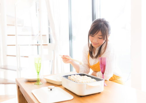 ホットプレートで餃子を焼く女性の料理風景