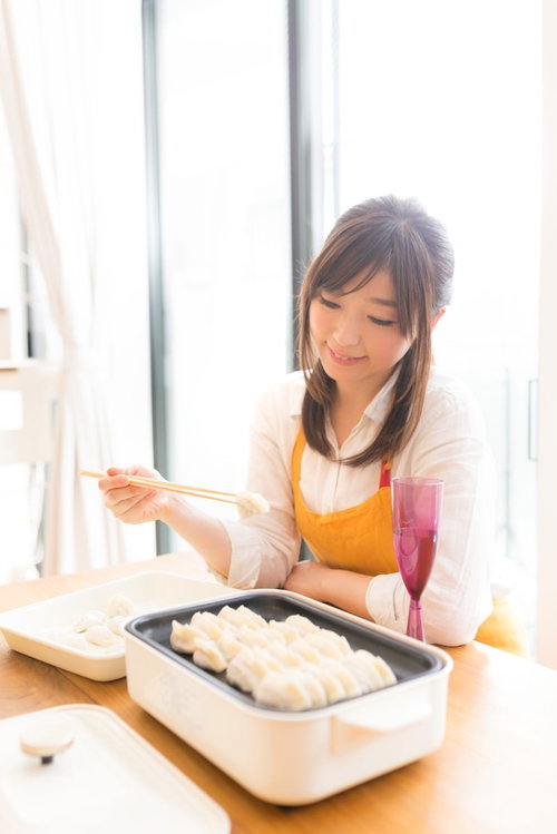 夫の大好きな餃子を箸で食べようとする専業主婦