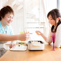夫婦で餃子作り、木のテーブルで仲良く味見の写真