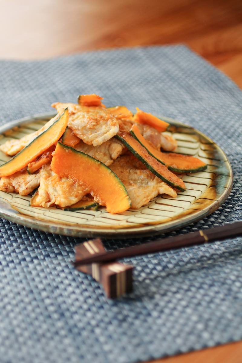 竹製の丸皿に豚肉とかぼちゃの生姜焼きが盛られ箸が添えられている