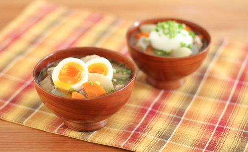 半熟卵とにんじんが入った木の椀の豚汁
