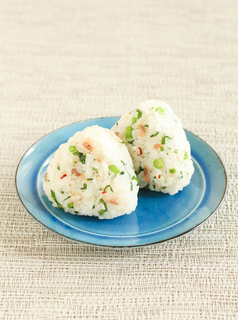 青い丸皿に緑の野菜と茶色の具材が混ざったおにぎりが3個盛られている