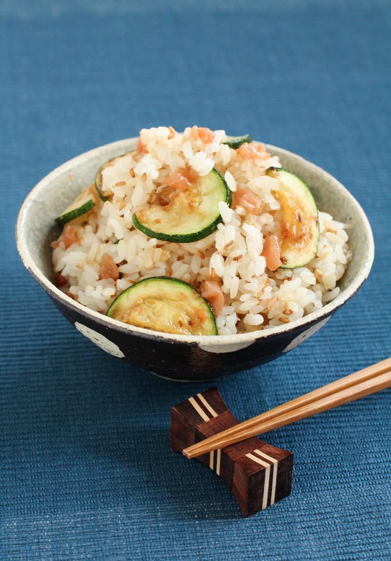陶器の茶碗に白いご飯とズッキーニや具材が混ざった混ぜごはんと箸が添えられている