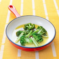 オレンジ色のフライパンで煮込むブロッコリーの写真