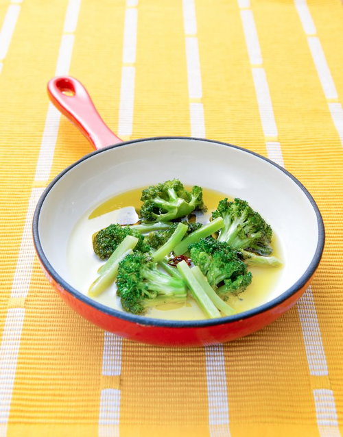 オレンジ色のフライパンで煮込むブロッコリー