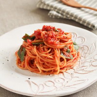 緑の葉がトッピングされたトマトソースパスタの写真