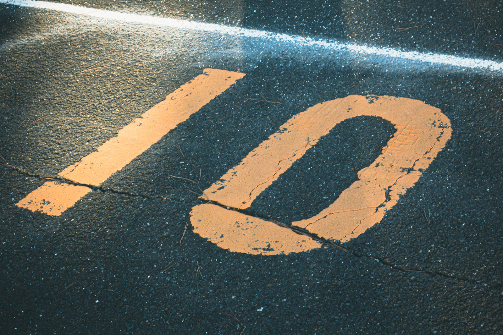 黒いアスファルトの路面にオレンジ色でペイントされた駐車場番号10