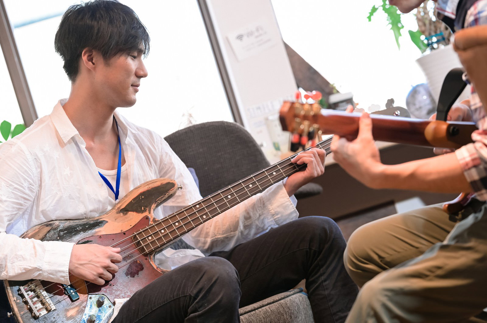 ベース教室で白いシャツの男性がベースを演奏している様子［モデル：村田裕章］