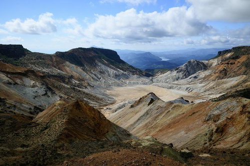沼ノ平火口の荒れた地表と遠方の山並み