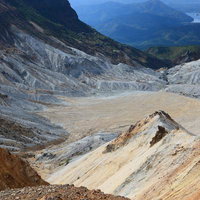 沼ノ平火口の荒れた大地と遠く見える山々のクレーターの写真