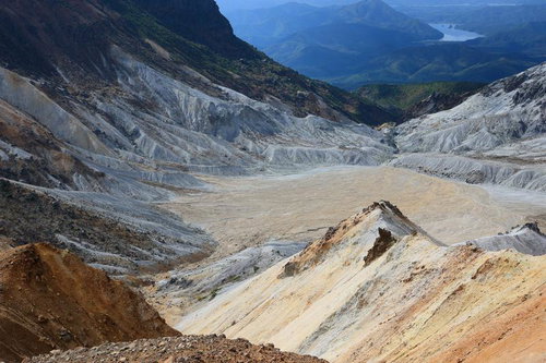 沼ノ平火口の荒れた大地と遠く見える山々のクレーター