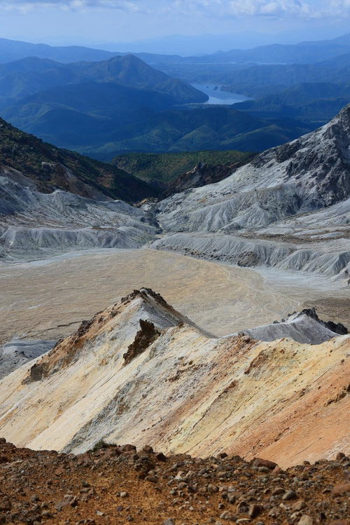 沼ノ平火口の荒涼とした地形と遠方の湖の景観