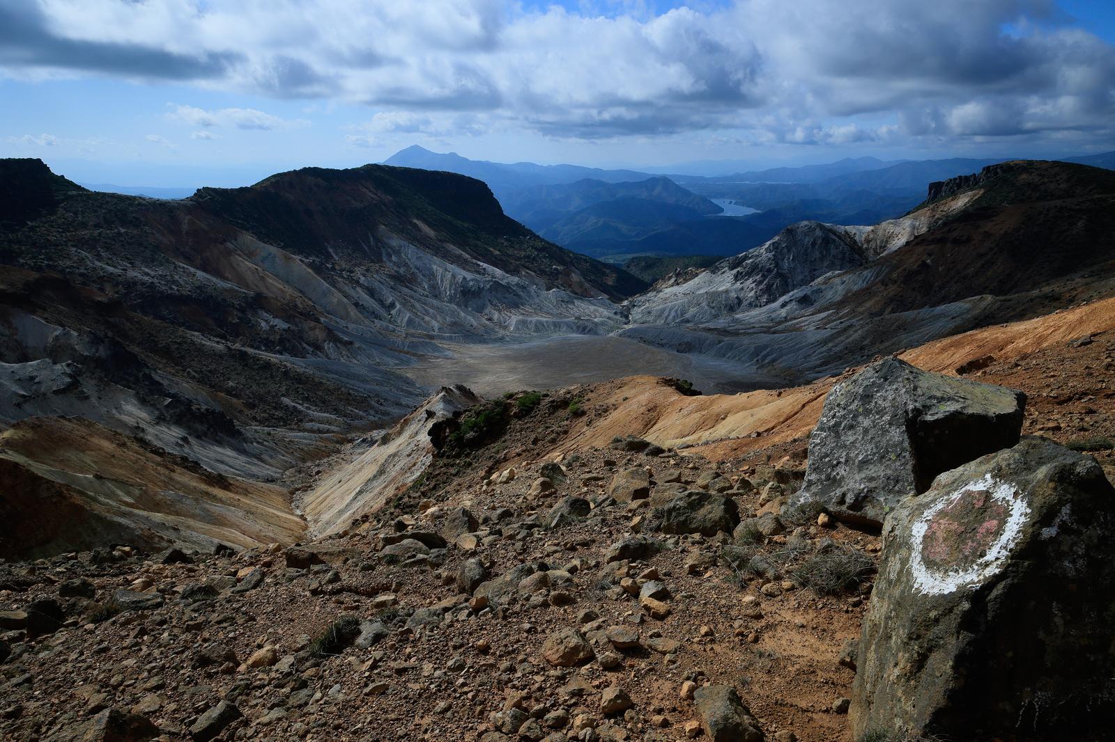 沼ノ平火口の荒涼とした大地。奥には山々と湖が見える