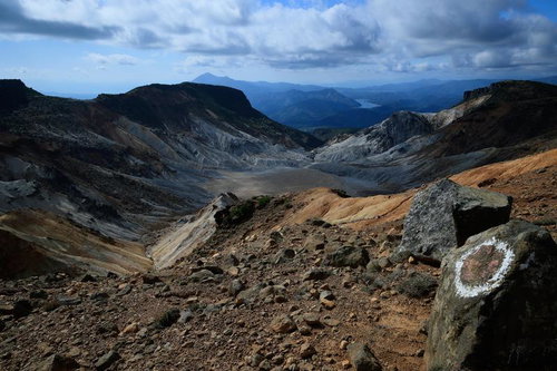 沼ノ平火口の荒涼とした大地と遠方の湖を高所から俯瞰