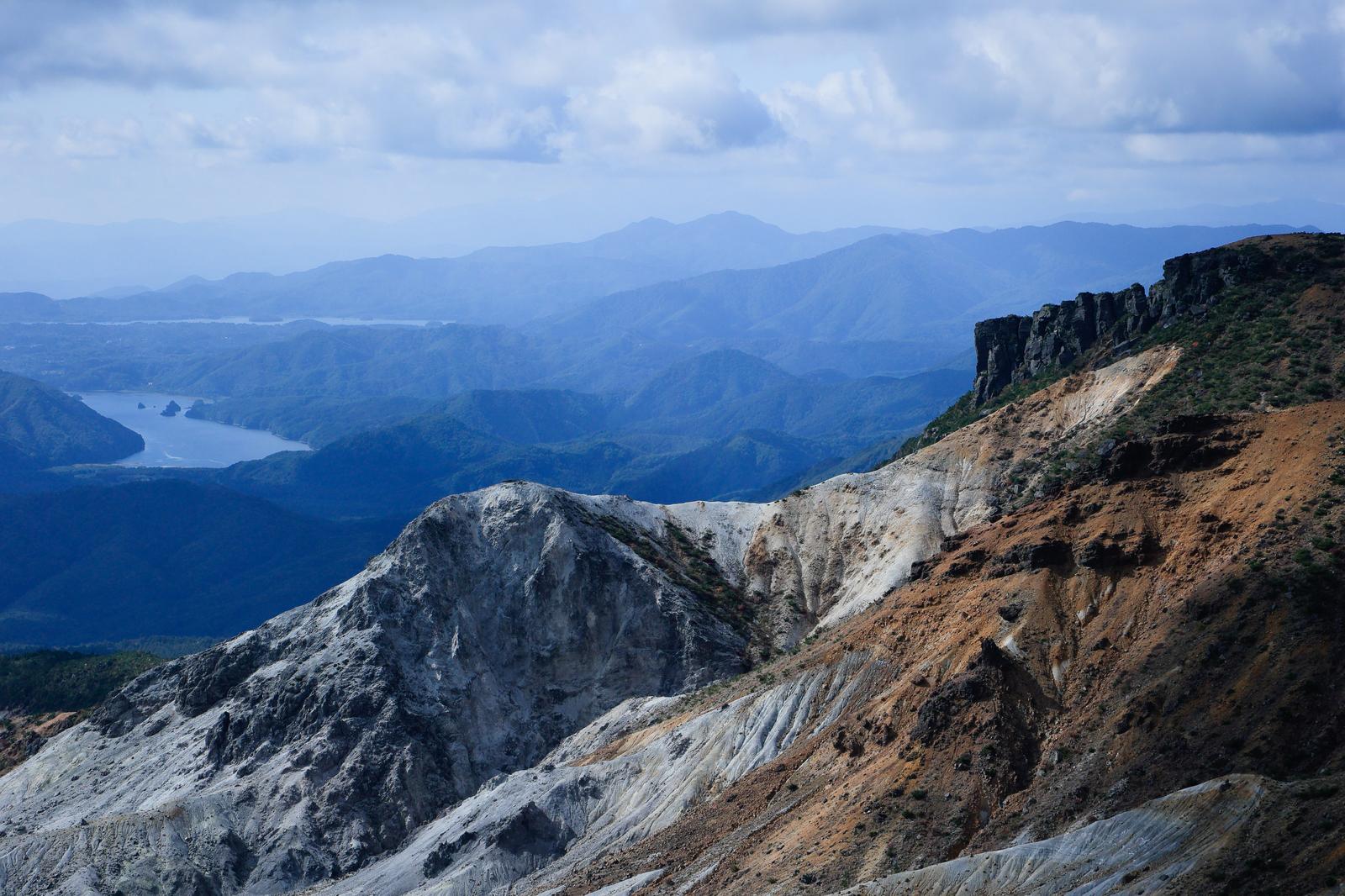 沼ノ平火口の白く露出した岩肌と遠景の山々や湖