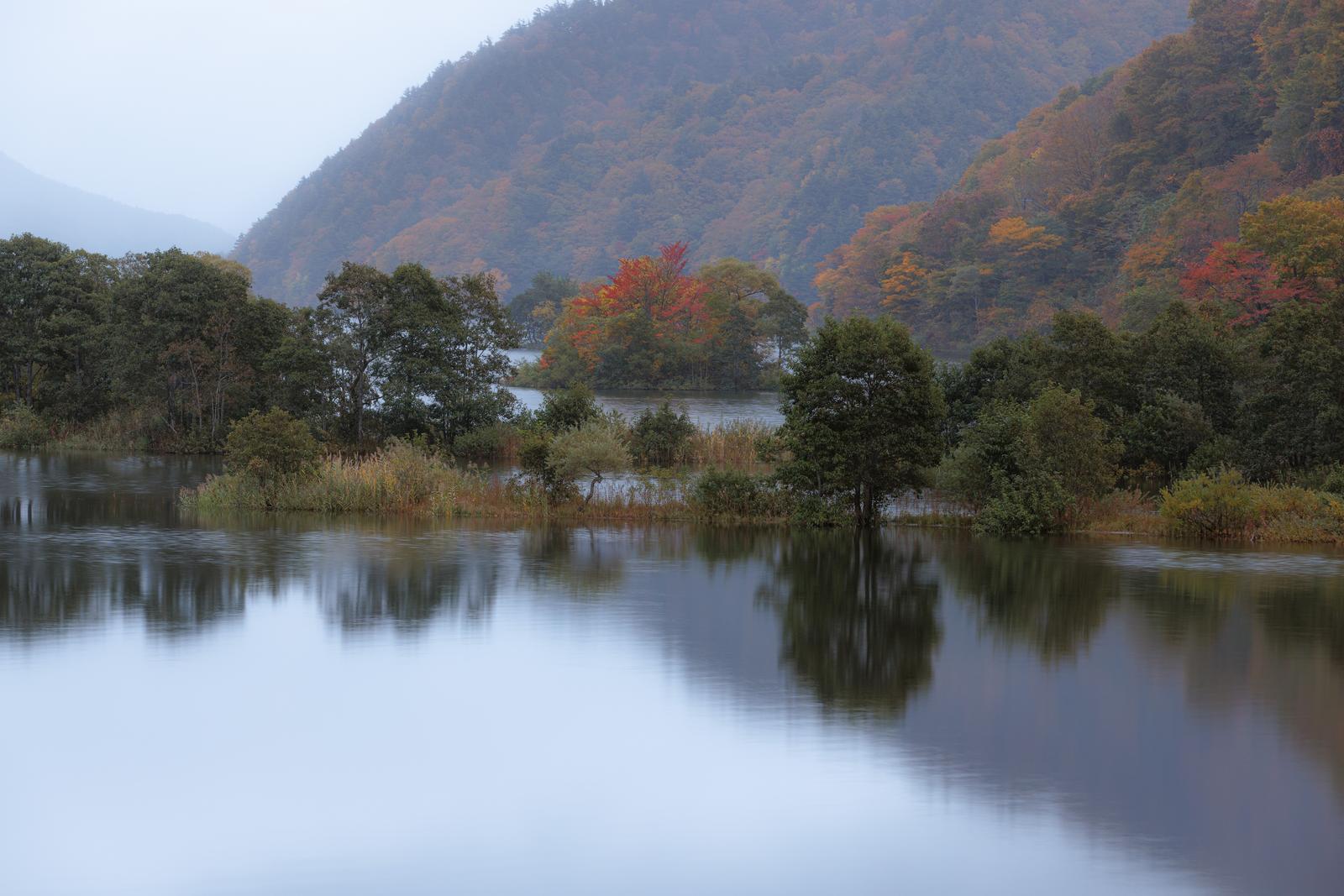秋元湖の湖面に秋の紅葉が映り込む風景