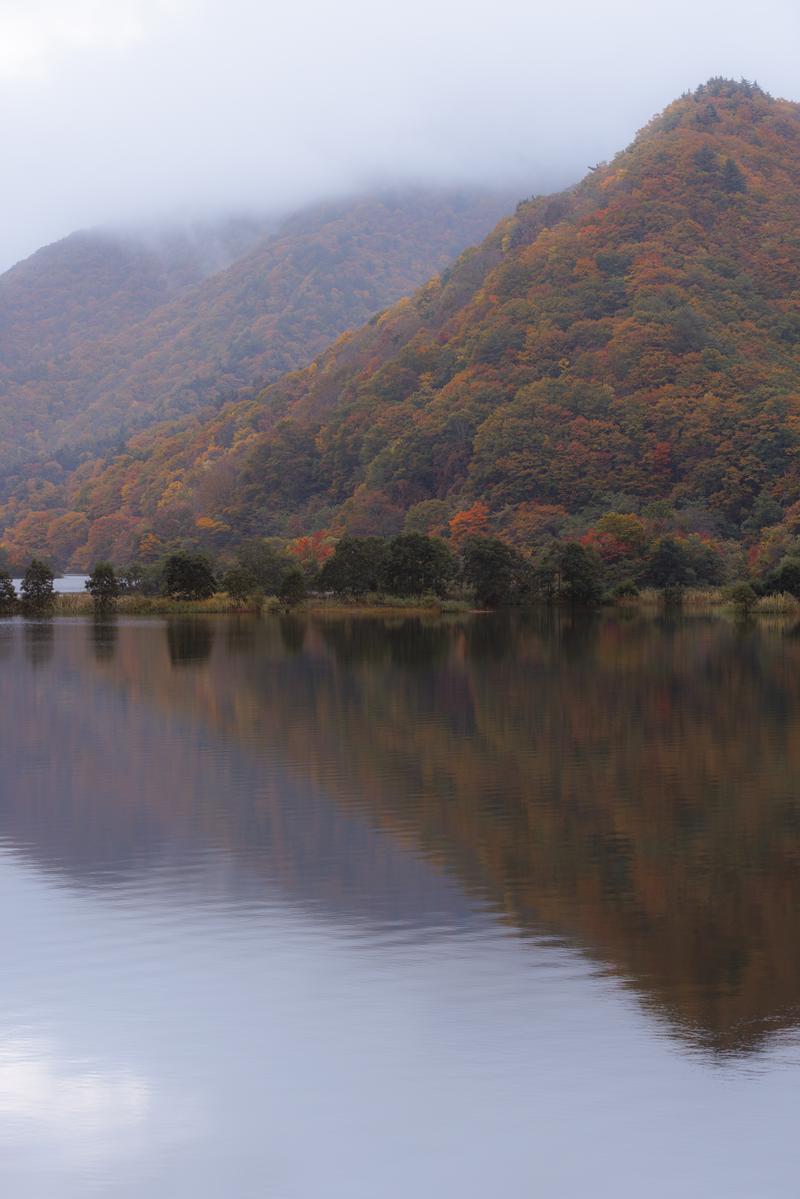 秋元湖に映る紅葉した山々、湖面に反射する色付く樹々