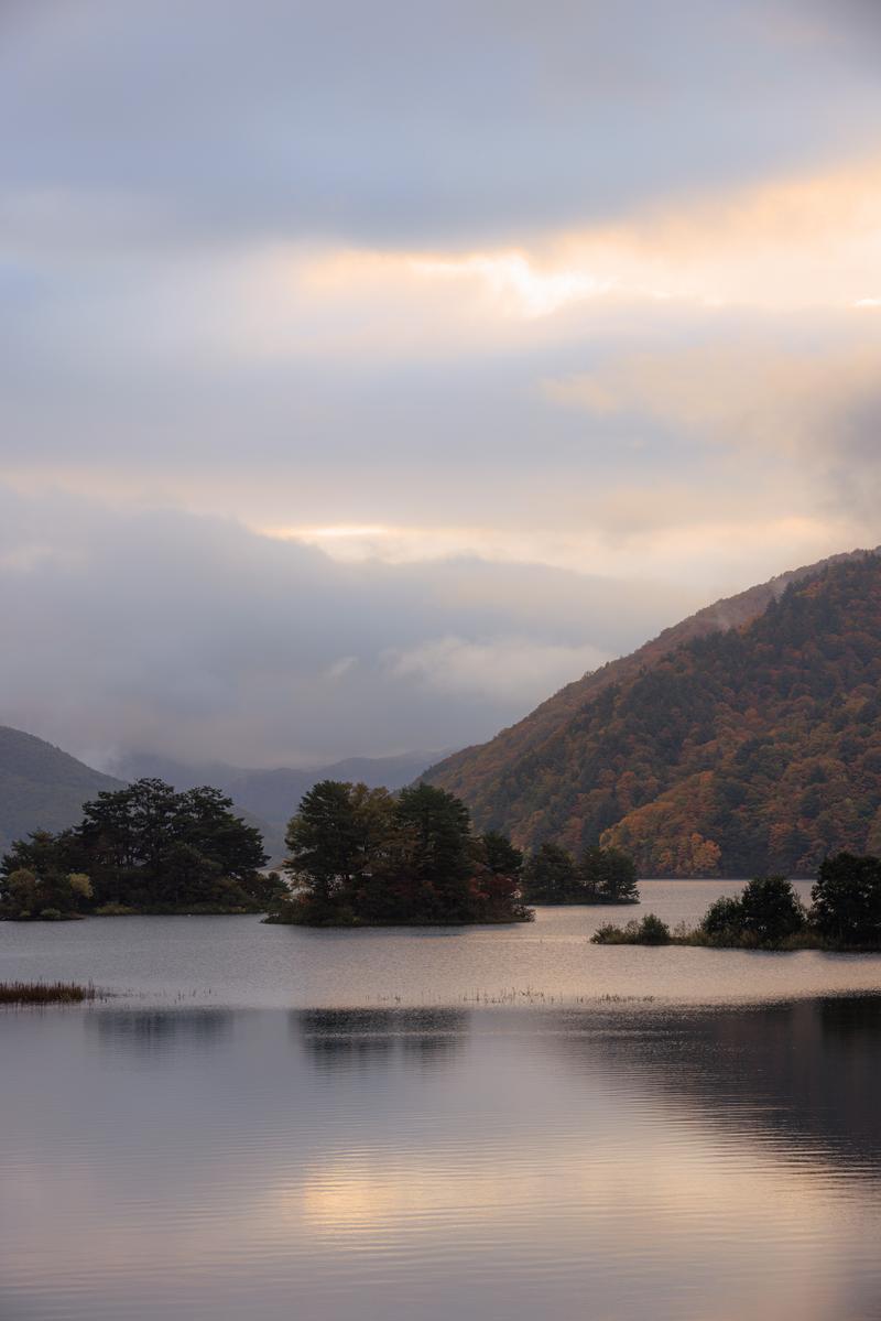 秋元湖の湖面に映る朝焼けと紅葉した山々