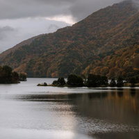 秋元湖の湖面に映る秋紅葉、薄明の静寂と山並みの写真