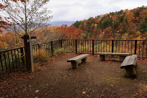 沼尻ルートの展望ベンチで眺める秋の紅葉と朝靄の山並み