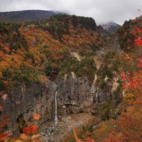 断壁に囲まれた白糸の滝と安達太良山の秋の紅葉の写真