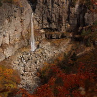 秋の断壁に映える白糸の滝と紅葉、沼尻ルートの渓谷風景の写真