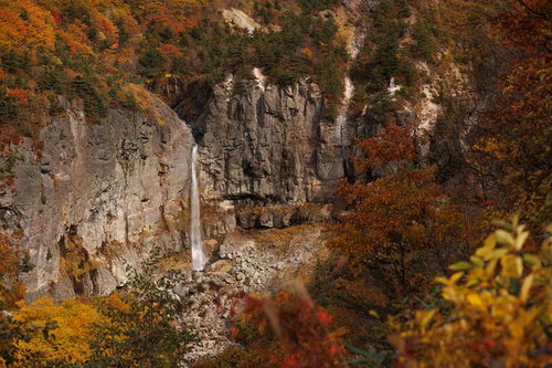 秋の白糸の滝、断壁に流れ落ちる水と紅葉に彩られた渓谷