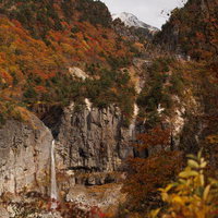 紅葉に包まれた秋の断壁と白糸の滝（猪苗代町）の写真