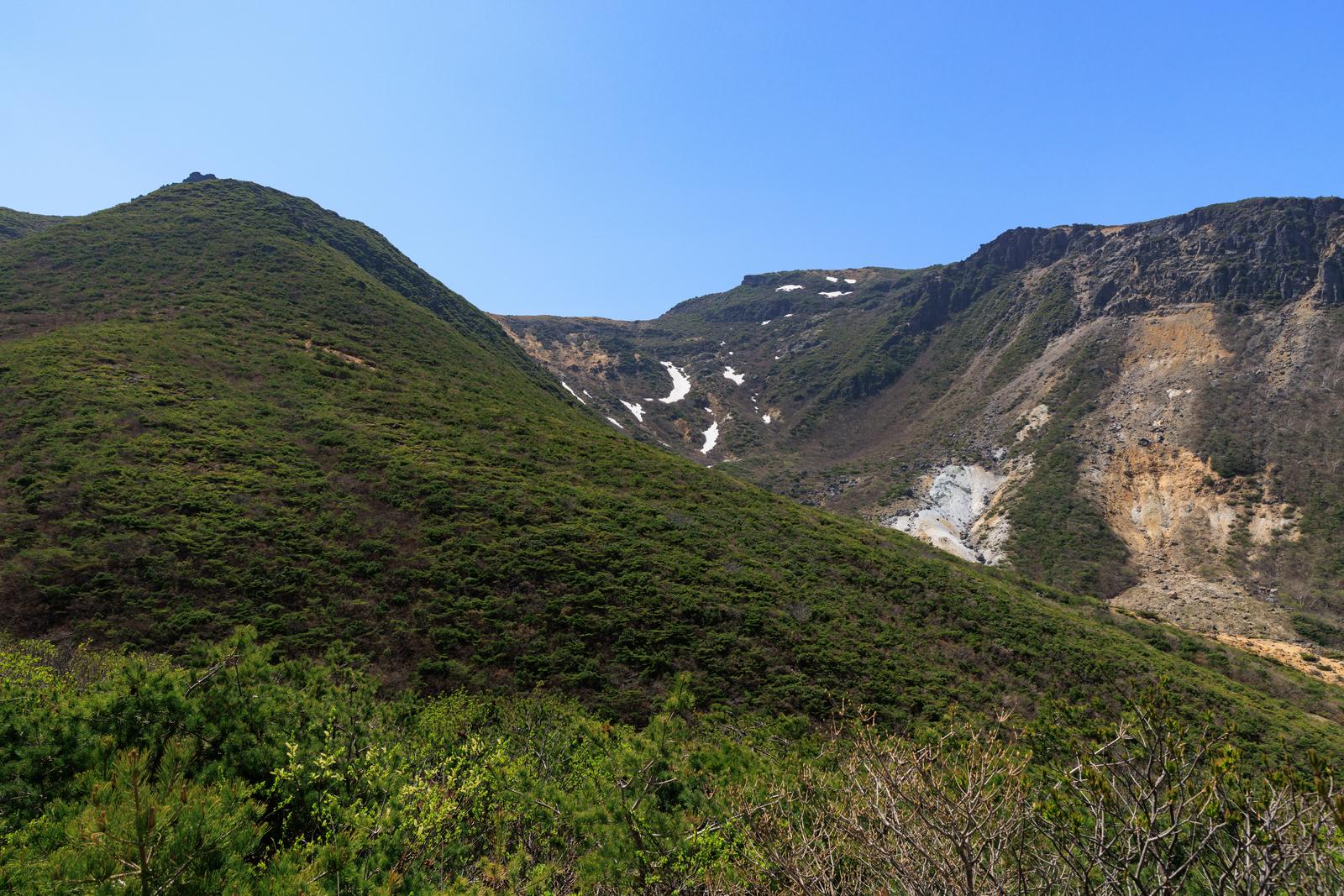 安達太良山の勢至平から見た新緑の山々と雪渓が流れる谷間