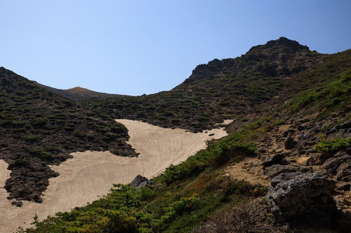 勢至平の新緑と雪渓が残る沢の風景