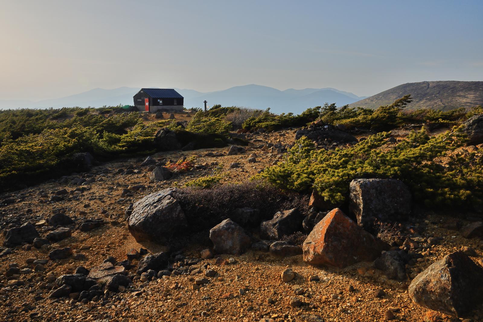 稜線上に建つ鉄山避難小屋と登山道