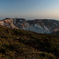 新緑に包まれた夕焼けと鉄山避難小屋周辺の山々の風景の写真