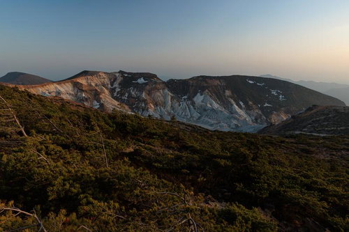 新緑に包まれた夕焼けと鉄山避難小屋周辺の山々の風景