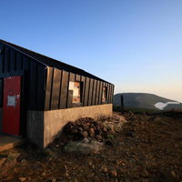 朝日に照らされる安達太良山の鉄山避難小屋の写真