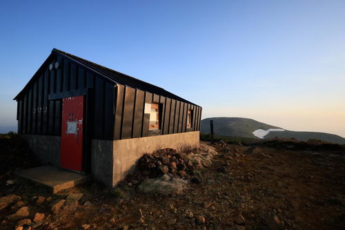 朝日に照らされる安達太良山の鉄山避難小屋