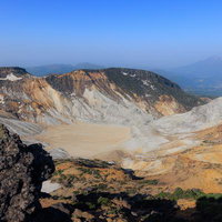 安達太良山の沼ノ平火口を望む荒涼とした山肌と新緑のコントラストの写真