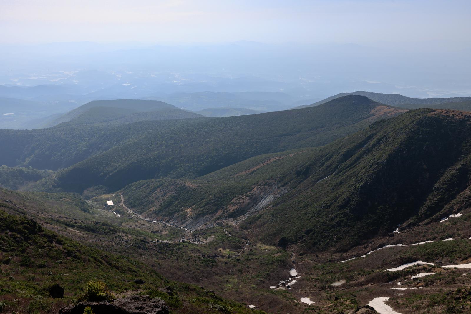 安達太良山周辺の山々が新緑で覆われ、谷間に流れる水が見える眺望