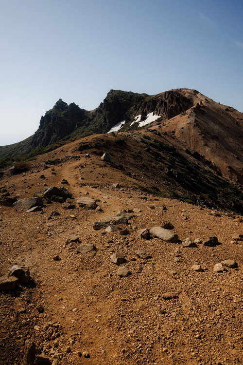 残雪が残る矢筈森の登山道と新緑の風景、火山地形の荒涼とした稜線