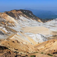 安達太良山の沼ノ平火口から望む秋元湖と荒涼とした火山地形の写真