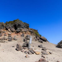安達太良山の山頂標が立つ岩場と青空、登山の到達点の写真